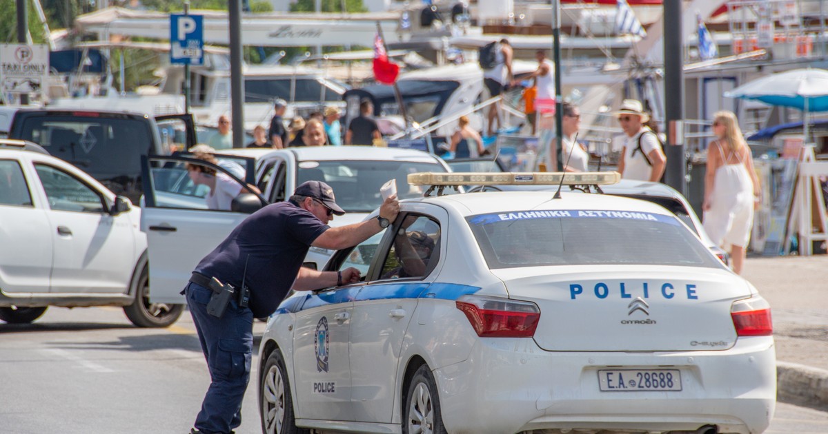Polițist grec sprijinit de o mașină de Poliție, în Grecia, în zona feribotului din Skiathos