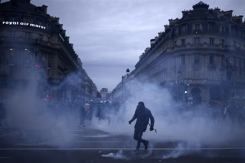 epa10539120 A protester stands in tear gas fumes during clashes with anti-riot police as thousands of people participate in a protest against the government's reform of the pension system in Paris, France, 23 March 2023. Protests continue in France after the prime minister announced on 16 March 2023 the use of Article 49 paragraph 3 (49.3) of the French Constitution to have the text on the controversial pension reform law - raising retirement age from 62 to 64 - be definitively adopted without a vote. EPA-EFE/YOAN VALAT