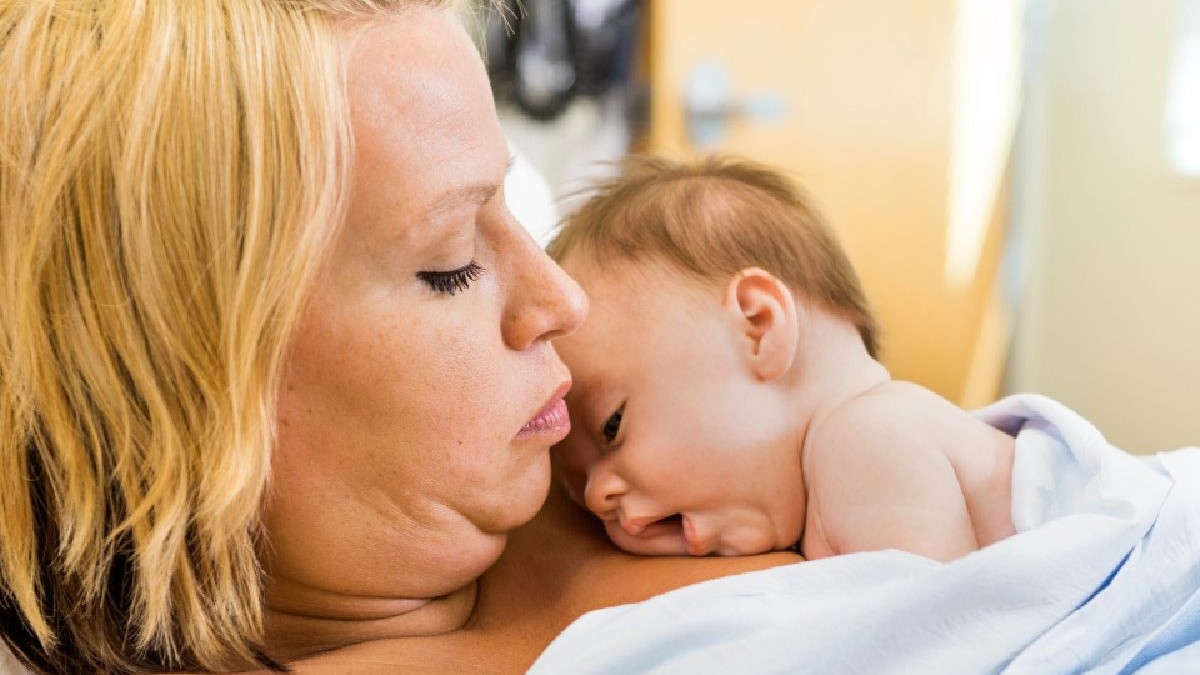 O mama sta in salon cu bebelusul la piept. Metoda Cangur, piele pe piele. Mama si nou nascut. Foto Imago