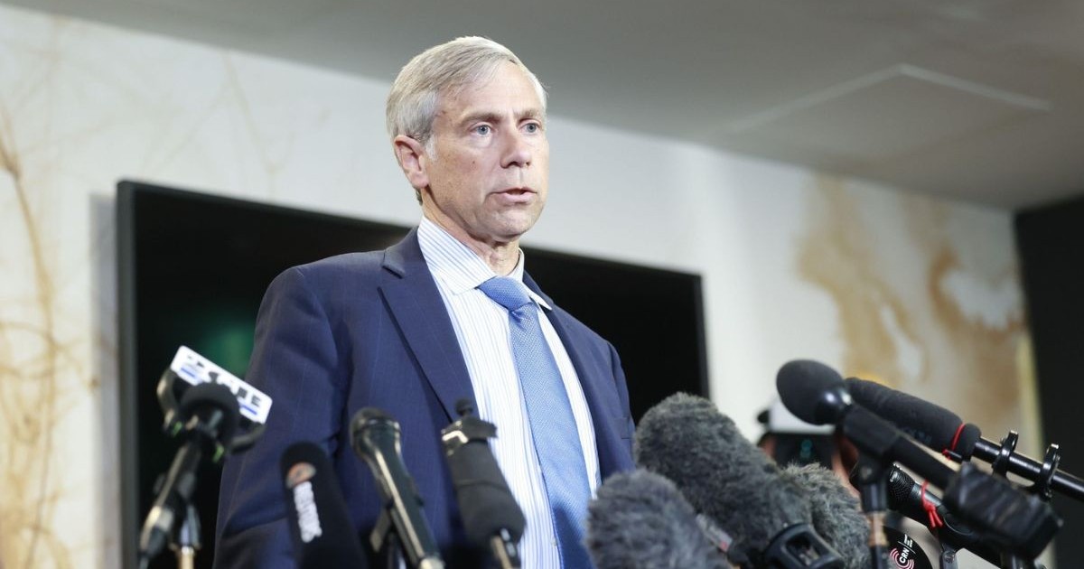 Barry Pollack îmbrăcat într-un sacou bleumarin, cu o cămașă albă și o cravată bleu, în timpul unei conferițe de presă. iulie 2024