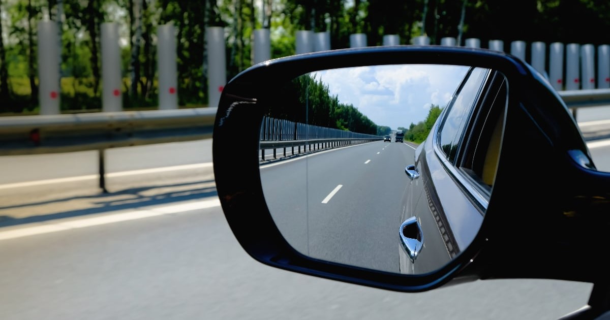 O oglindă laterală a unei mașini, pe autostradă.