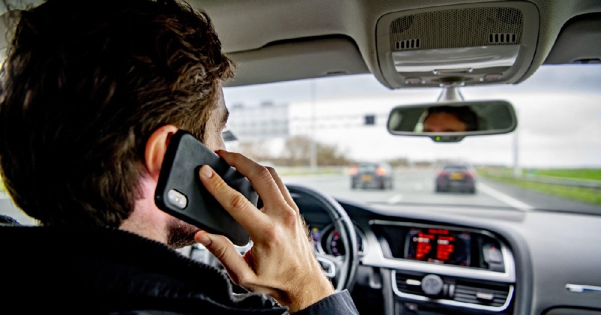 Un bărbat folosește un telefon mobil în timp ce conduce