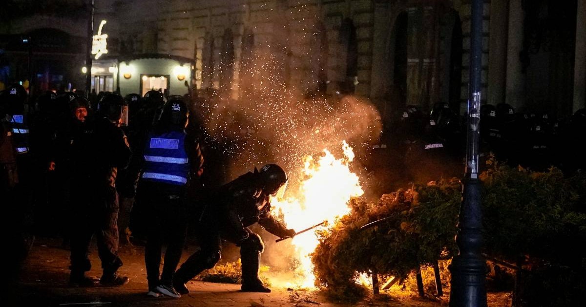 Mai mulți bărbați intervin pentru a stinge un incendiu in Centrul Vechi din București, în timpul unui protest, pe 9 martie 2025.