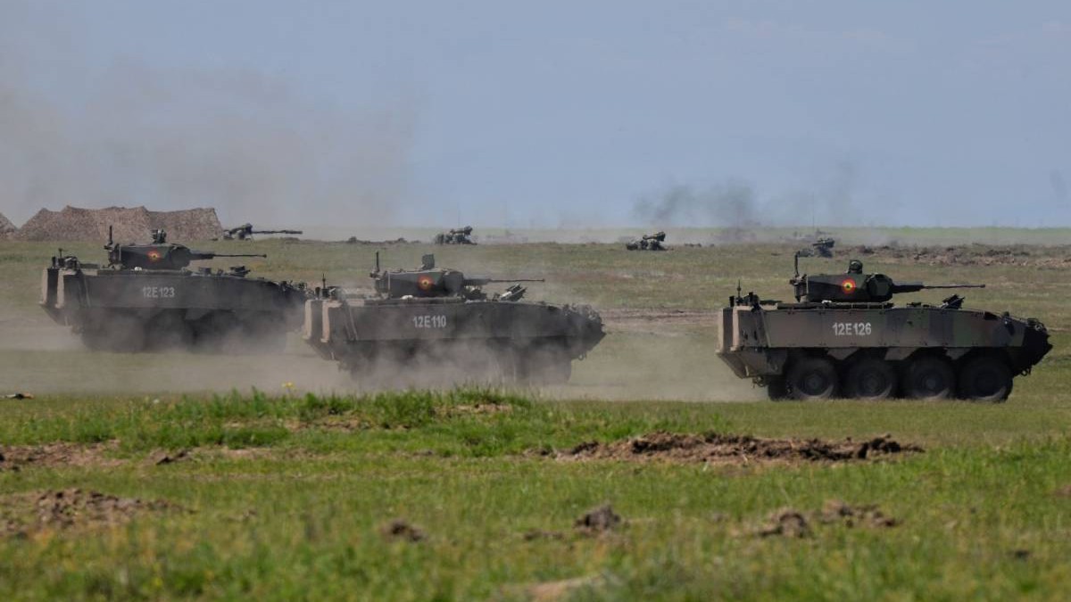 Trei tancuri românești mergând într-o zonă de câmpie și lansând atacuri în timpul unui exerciți militar în România