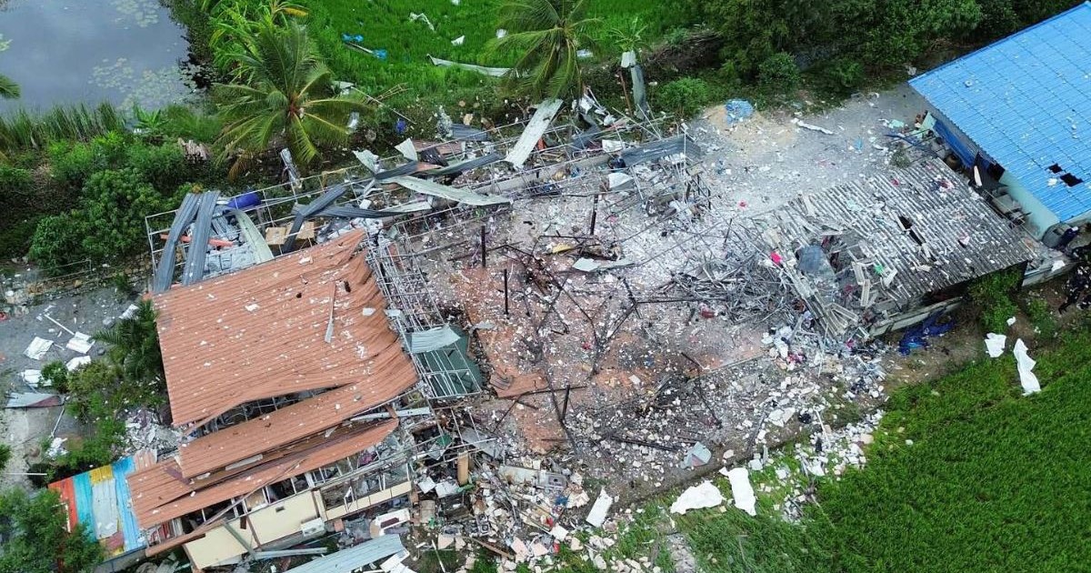 rămășițele unei fabrici de artificii din Thailanda după o explozie - în imaginea realizată din dronă se vede o clădire cu acoperiș de tabla de culoare portocalie, înconjurată de funingine și bucăți de lemn și de metal