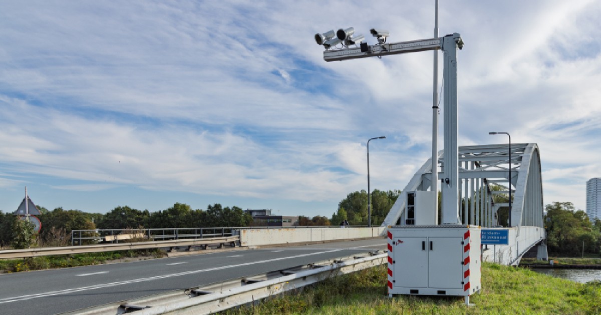 O unitate de camere mobile pentru monitorizarea traficului, utilizarea telefonului și aplicarea legii, poziționată pe un mal înverzit lângă un pod rutier și arcuit, în Țările de Jos.