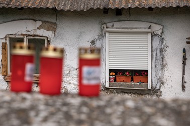 Pe zidul de piatră ce împrejmuieşte curtea, oamenii din Ungra au aprins trei candele roşii