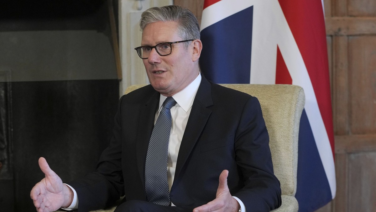 Imagine cu premierul Keir Starmer stând pe scaun. Poartă un costum negru, o cămașă albă și o cravată închisă la culoare cu buline albe