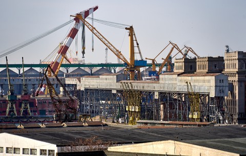 Imagine din Portul Constanța, acolo unde se vedem cum macaralele încarcă mai multe containere pe o navă cargo