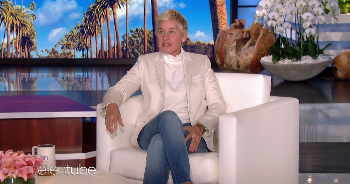 Ellen Degeneres, stând pe un fotoliu alb, îmbrăcată într-un sacou alb, o bluză albă și o pereche de jeans albaștri, pe platoul fostei sale emisiuni The Ellen DeGeneres Show