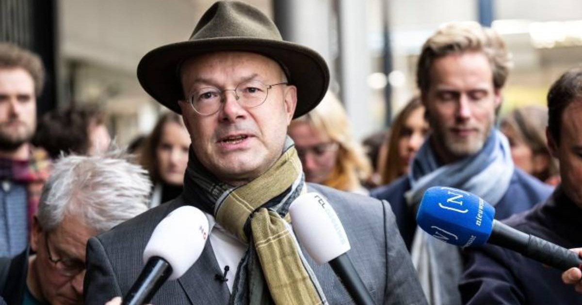 Donald Pols cu pălărie, ochelari și fular vorbește în fața mai multor microfoane, înconjurat de jurnaliști și de alte persoane. directorul a fost concediat de Tata Steel după o singură zi de muncă.