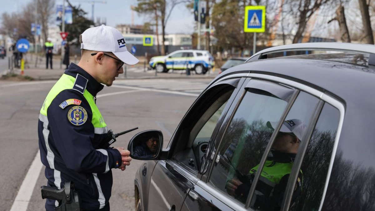politist rutiera imbracat in uniforma in dreptul unei masini oprite pentru un control de rutina
