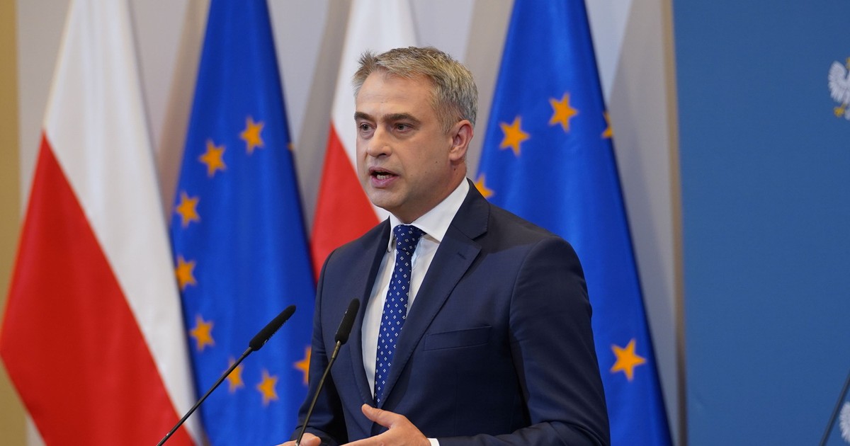 ministru Krzysztof Gawkowski polonia in timpul unui discurs, in spatele lui sunt steagurile poloniei si al ue