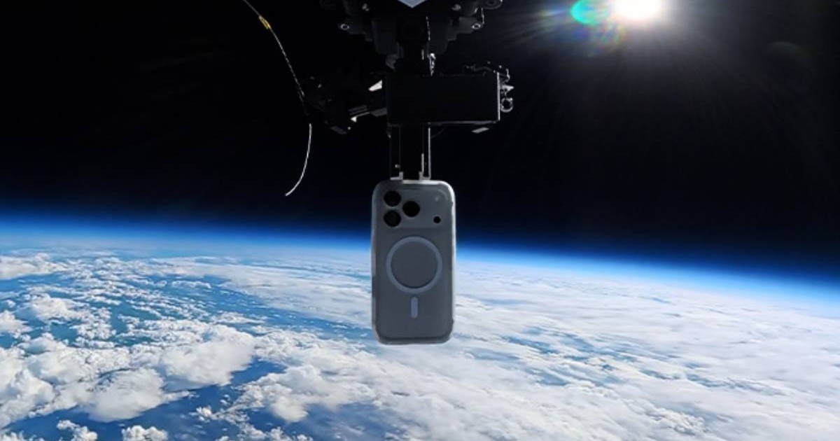 Un iPhone 17 Pro protejat de o husă este suspendat la mare altitudine, deasupra Pământului, înaintea testului de cădere din stratosferă. În fundal se vede curbura planetei, acoperită de nori, iar telefonul este prins de mecanismul balonului folosit în experiment.