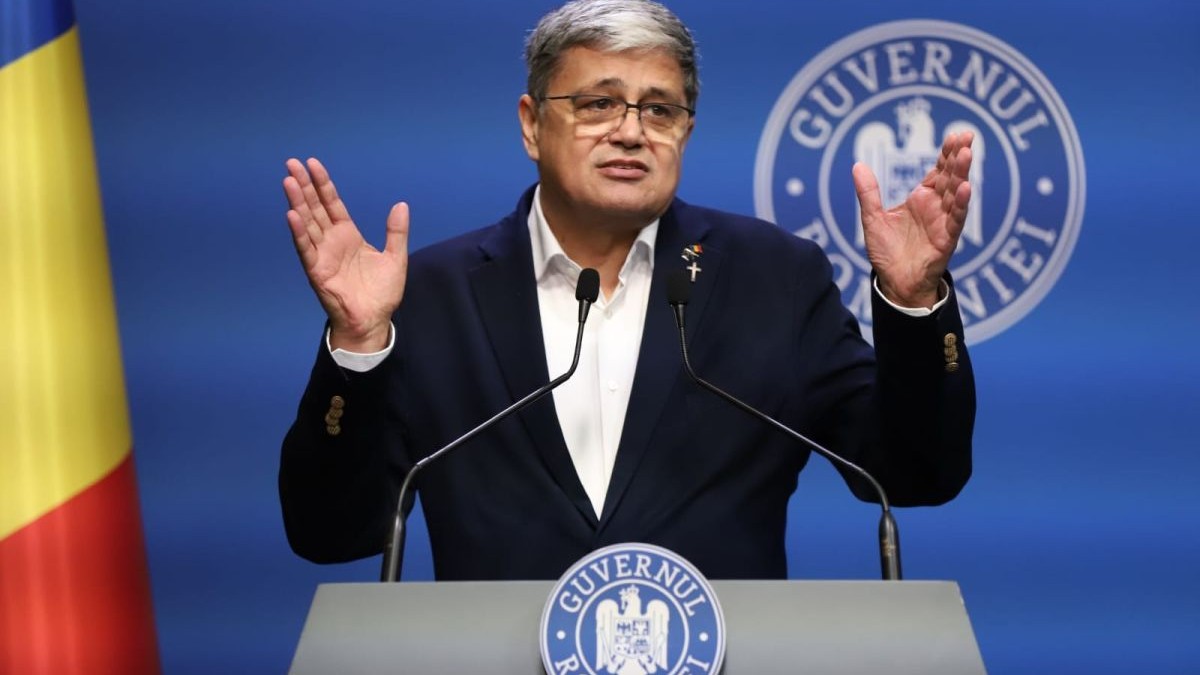 Ministrul Proiectelor Europene, Marcel Boloș, surprins când gesticulează din mâini și vorbește la microfon de la pupitrul Guvernului, la o conferință de presă, vineri, 30 mai 2025