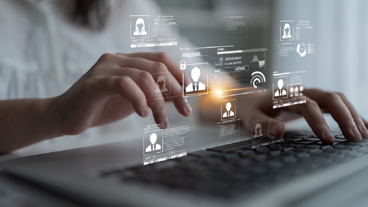 Cum afli ce date există despre tine pe internet și cum le ștergi - Imagine cu un bărbat in faţa unei tastaturi deaspra căreia se află un ecran virtual care sugerează datele personale ale unor persoane