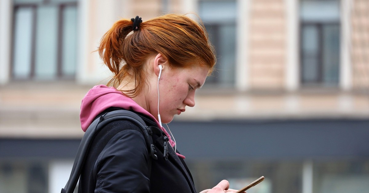 O fată se uită la telefonul mobil pe stradă Foto: Profimedia