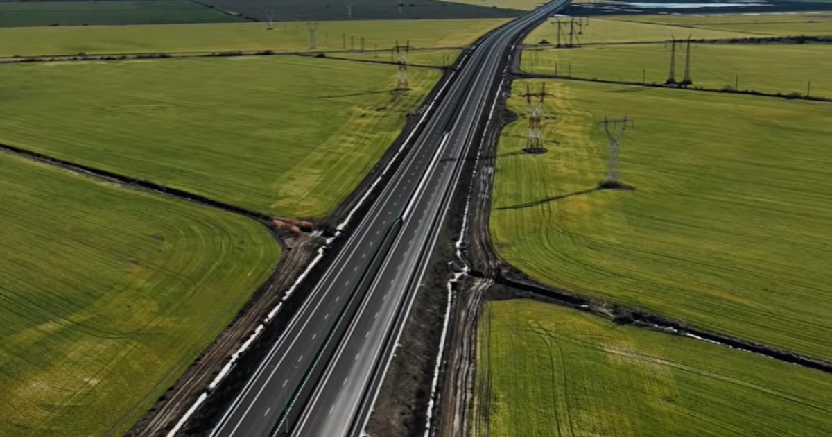 Imagine aeriană cu un sector al Drumului Expres Brăila – Galați, care traversează câmpurile din zonă pe o distanță lungă și dreaptă. De o parte și de alta a șoselei se văd terenuri agricole și stâlpi de electricitate, evidențiind traseul noii infrastructuri rutiere.