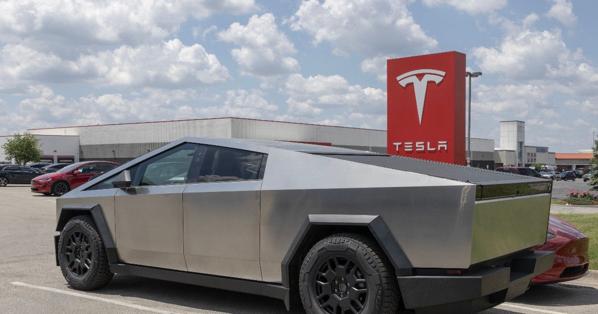 Un Tesla Cybertruck este parcat într-o zonă comercială, având designul său angular distinctiv și caroseria din oțel inoxidabil.