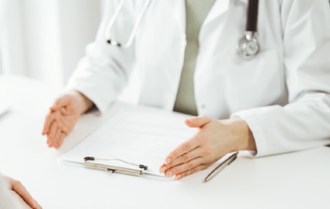 Doctorul și pacientul stând și discutând ceva unul lângă celălalt la biroul alb din clinică
