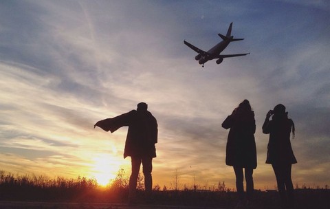 Siluete privesc un avion care aterizează pe fundalul unui apus de soare strălucitor - zboruri, vacanțe de toamnă, turism