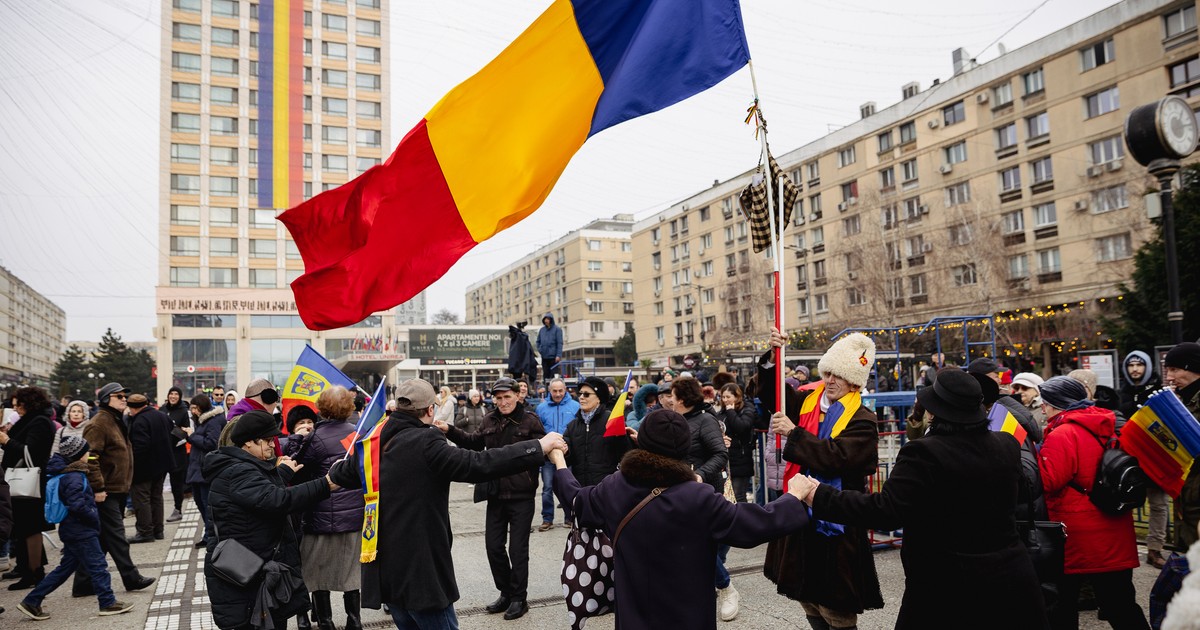 Oameni prinși în horă în Piața Unirii din Iași având în mijloc un steag tricolor uriaș