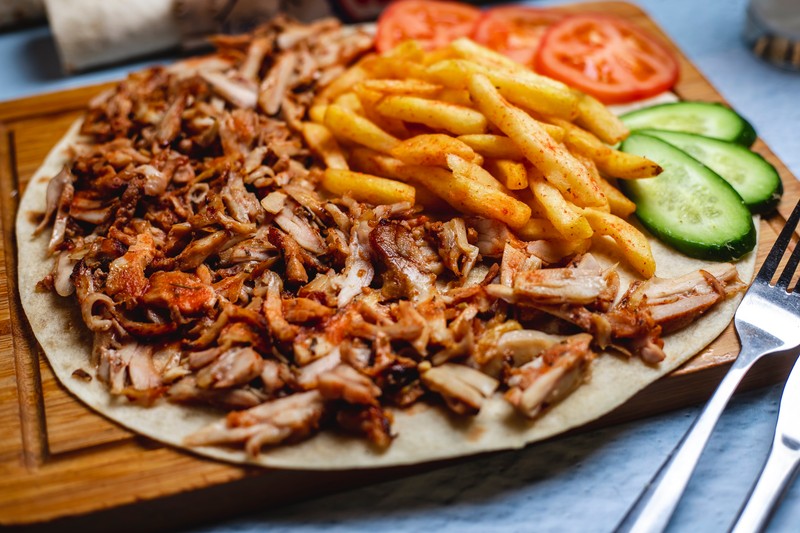 side view iskander doner on pita with french fries fresh cucumber and tomato