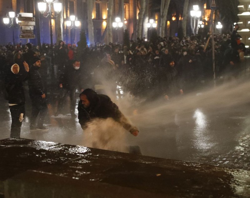 Imagine simbolică pentru 2023, la protestele din Georgia: manifestanți strânși în jurul steagului UE, fluturat de o femeie pe care autoritățile au pus tunul cu apă - VIDEO