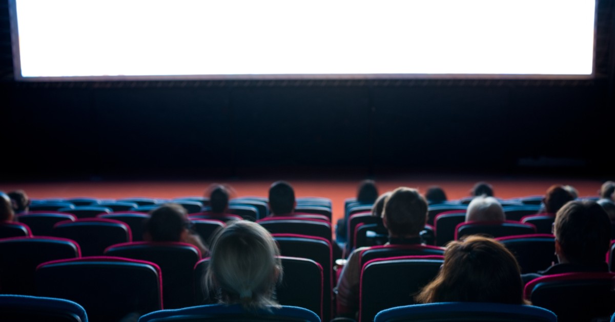 Oameni care se află pe scaune într-o sală de cinema