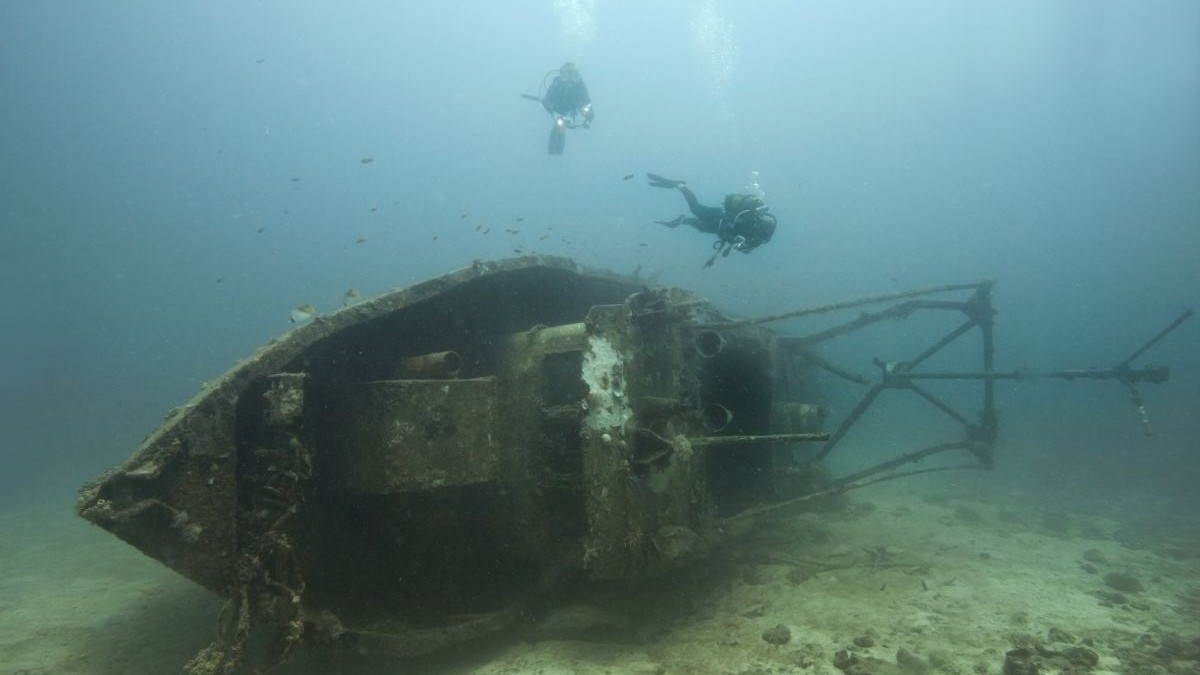 Doi scafandri înoată lângă o epavă sub apă, în Madagascar