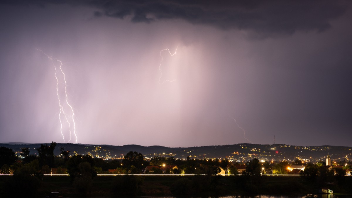 Fulgere în timp ce luminează cerul deasupra unui sat din România, în timpul unei furtuni