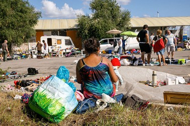 O femeie din tabără vinde obiecte, majoritatea colectate din tomberoane, la un târg de vechituri din Bari organizat în fiecare duminică