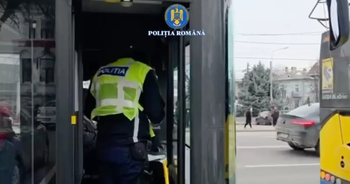 În imagine se vede un polițist care urcă într-un mijloc de transport public, aparent un autobuz sau troleibuz, pentru a efectua un control.