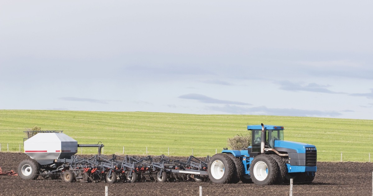 Un tractor albastru merge pe un câmp. Fotografie cu caracter ilustrativ.