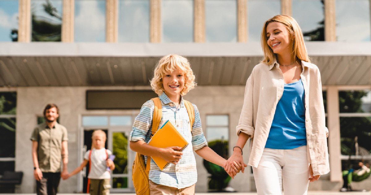 Părinții tineri își însoțesc copiii de la școală acasă după ore, la întoarcerea din vacanța de vară.