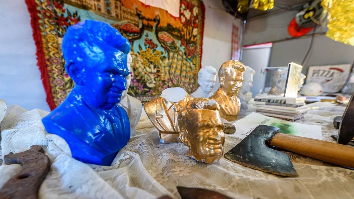Figurine cu bustul lui Nicolae Ceaușescu, unele aurii, altele albastre, alături un topor, asezate pe niste materiale textile
