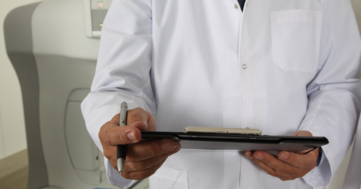 doctor cu documente în mână în fața unui aparat tomograf