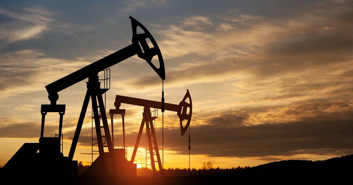 Două sonde de petrol funcționale care lucrează pentru extragerea țițeiului, în fundal se vede cum apune soarele