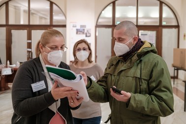 Cristian, votant la secția 158 de la Ambasada României la Berlin, și membrii comisiei de votare care îi arată lista de documente prin care poate dovedi că are reședința în Germania