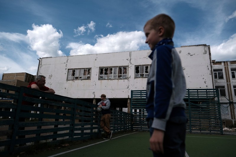 Un băiat se joacă în curtea școlii din Irpin care a fost avariată de invazia rusă. Foto: Profimedia