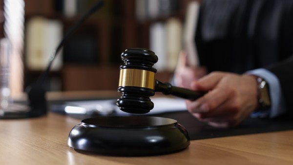 Judecător izbește cu un ciocănel în masa de lemn, într-o sală de judecată 