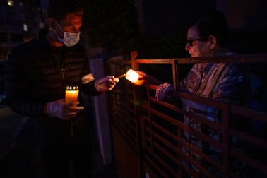 Iulian, purtând echipament de protecție, oferă Lumină unei bătrâne care a așteptat la poartă