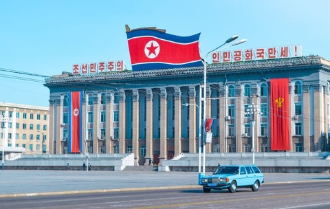 Pyongyang, Coreea de Nord – octombrie 2019 O mașină veche albastră circulând pe o stradă din Pyongyang, cu steagul Coreei de Nord
