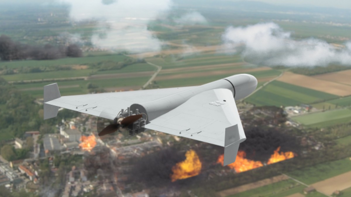 O dronă militară se află în zbor deasupra unei zone cu case și copaci. Două focare mari de incendiu sunt vizibile în peisaj, unul în partea din față a imaginii și celălalt în partea stângă, mai în spate.