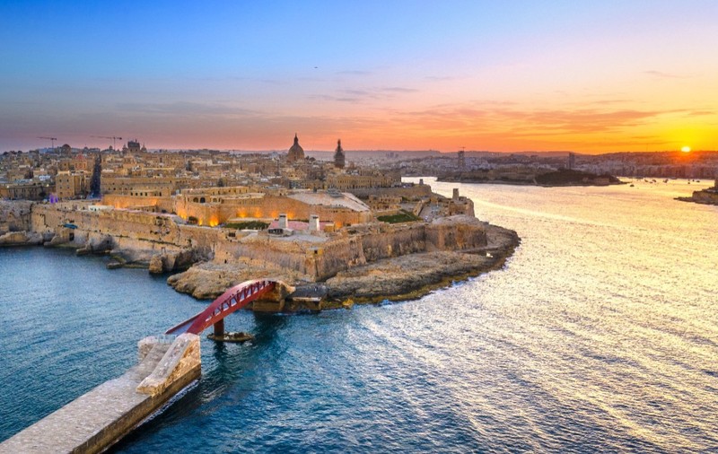 Imaginea prezintă o vedere aeriană asupra orașului istoric Valletta, capitala Maltei, văzută la apus de soare.