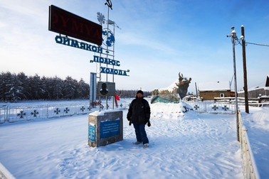Oymyakon, Yakutia - February 05 2018: A woman standing near stele in honor of the opening of the Pole of Cold in the Oymyakon. Bas-relief researcher Obruchev