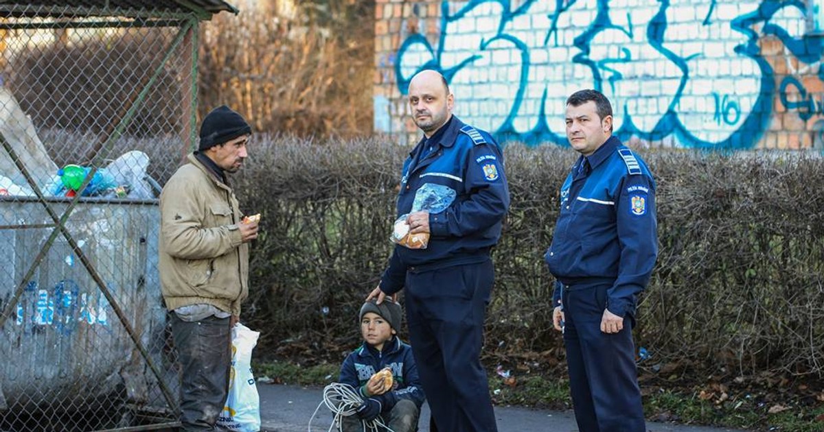 Doi poliţişti din Braşov, fotografiați hrănind nişte oameni ai străzii care scormoneau prin gunoaie