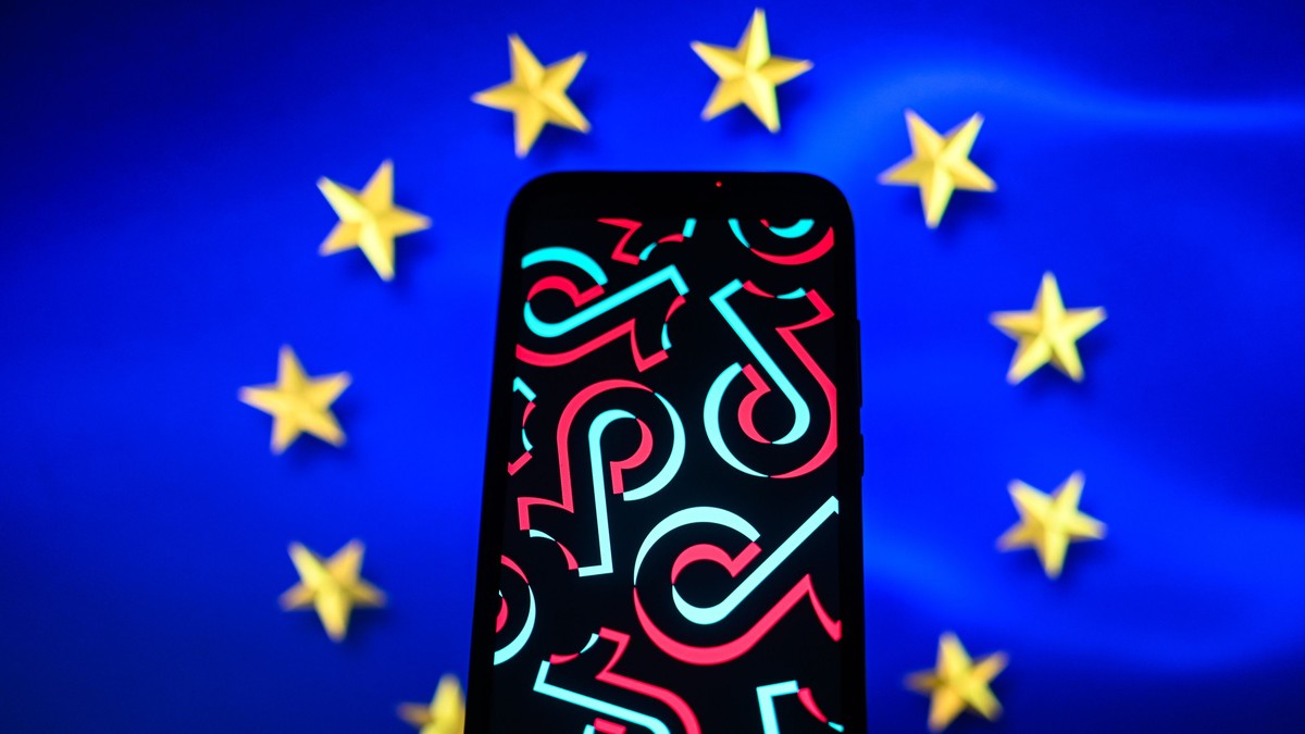 un telefon care afișează sigla TikTok, pe fundalul steagului Uniunii Europene
