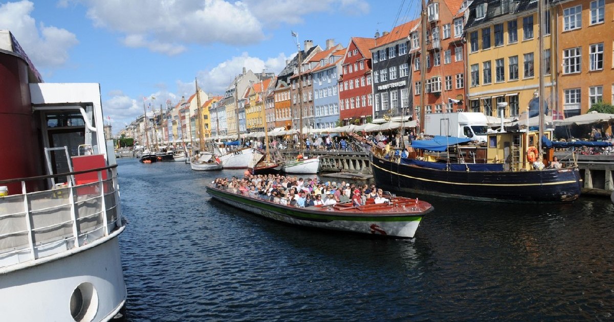 Copenhaga /Danemarca/06 august 2022/Turiști la cafenea, mâncând și bând și plimbându-se cu barca într-o zi însorită pe canalul Nyhvan din capitala daneză.