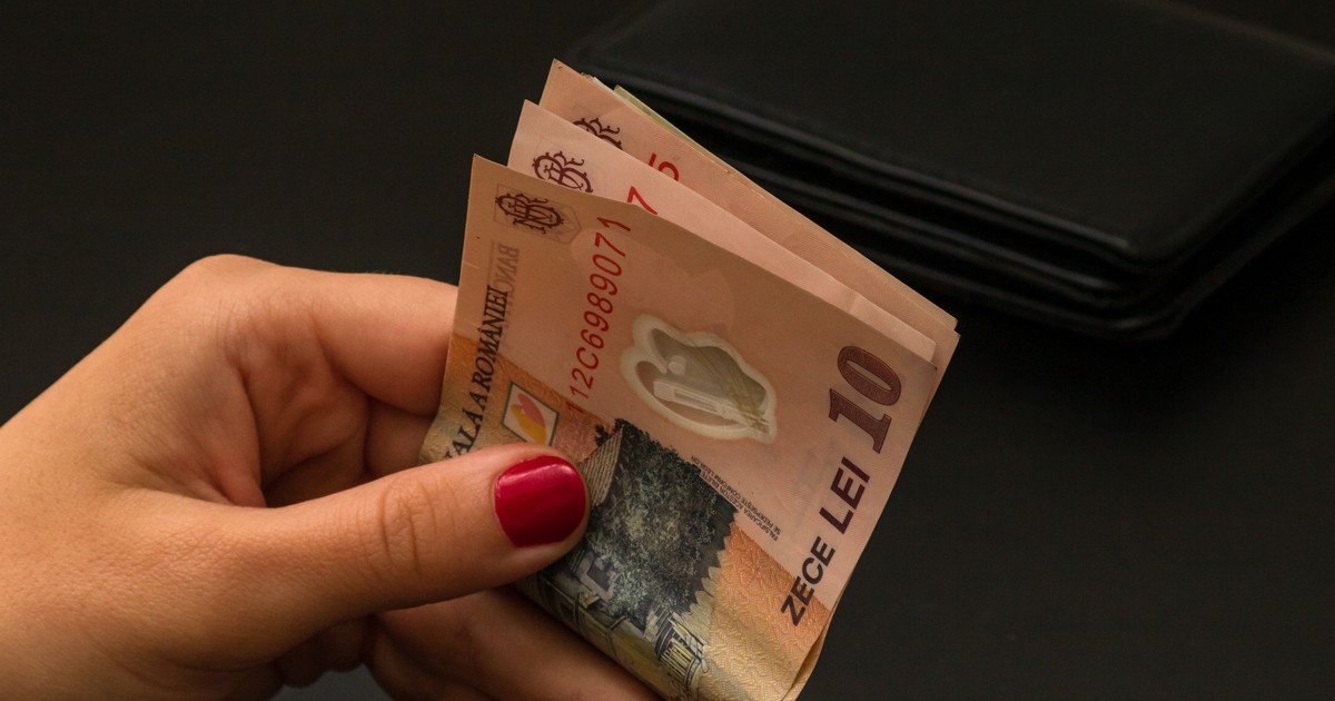 O mână ține mai multe bancnote de 10 lei românești, pliate, pe un fundal închis la culoare. Imaginea sugerează ideea de bani și finanțare, fiind potrivită pentru a ilustra o majorare de sume sau alocații.